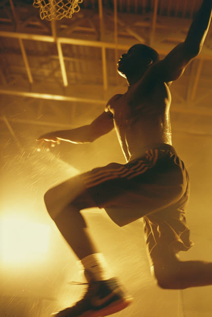 Basketball player mid-dunk in a dimly lit gym