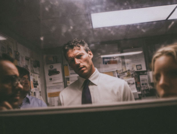 Man in shirt and tie framed in an office window