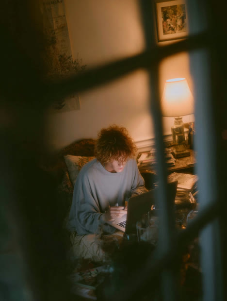Person writing at a desk, seen through a window frame