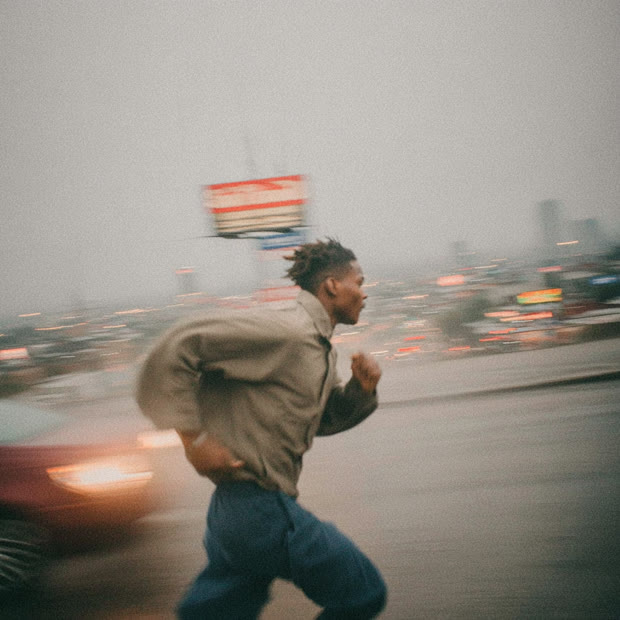 Runner sprinting past blurred city traffic