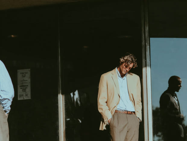 Man in a pale suit outside a storefront