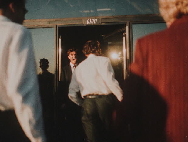 Man walking out through a doorway past onlookers