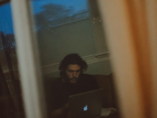 Person at a laptop seen through a reflective window